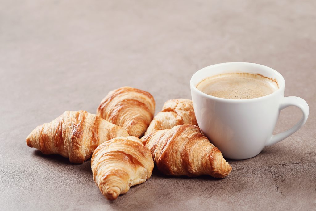 de délicieux croissants et une tasse de café posés sur la table