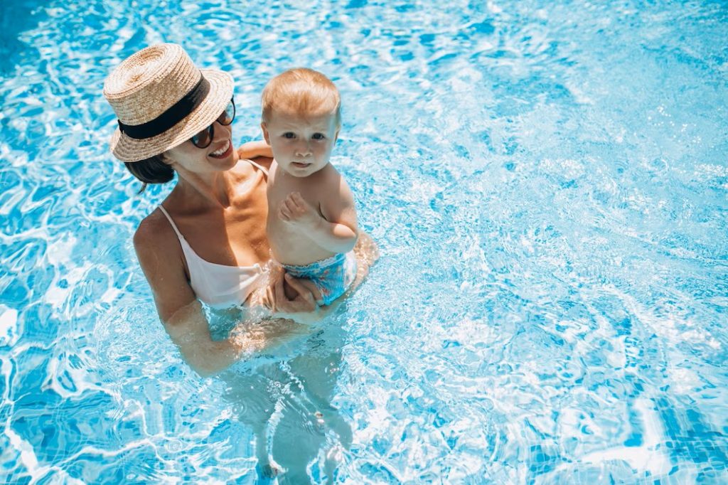 une mère tenant son fils dans une piscine ensoleillée